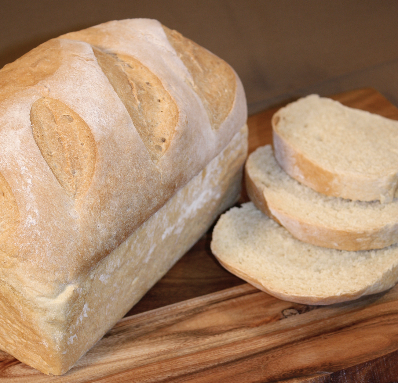 Farmhouse White loaf with soft sliced crumb on a wooden board