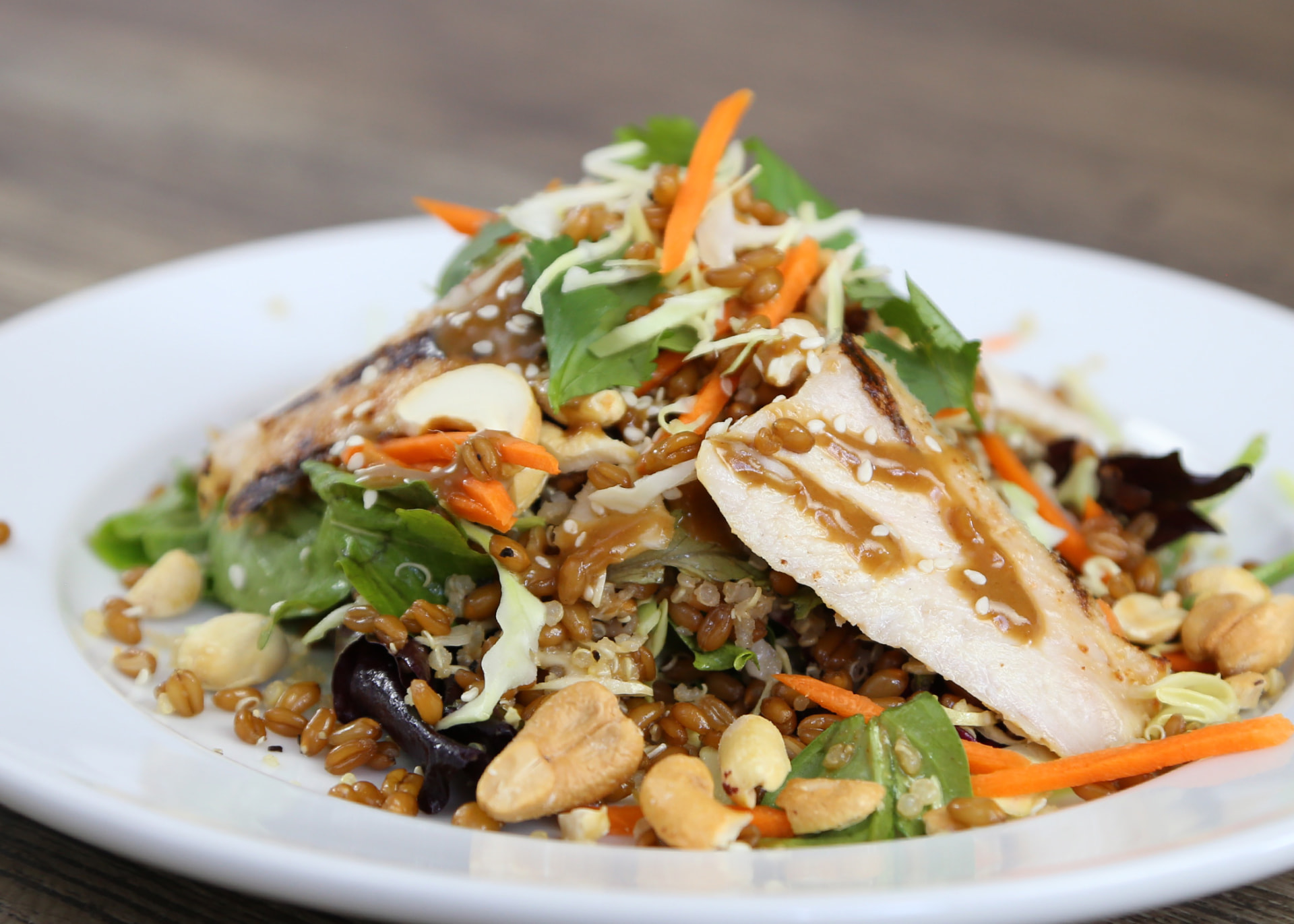 Sesame chicken salad with grilled chicken, mixed greens, carrots, cashews, and sesame dressing