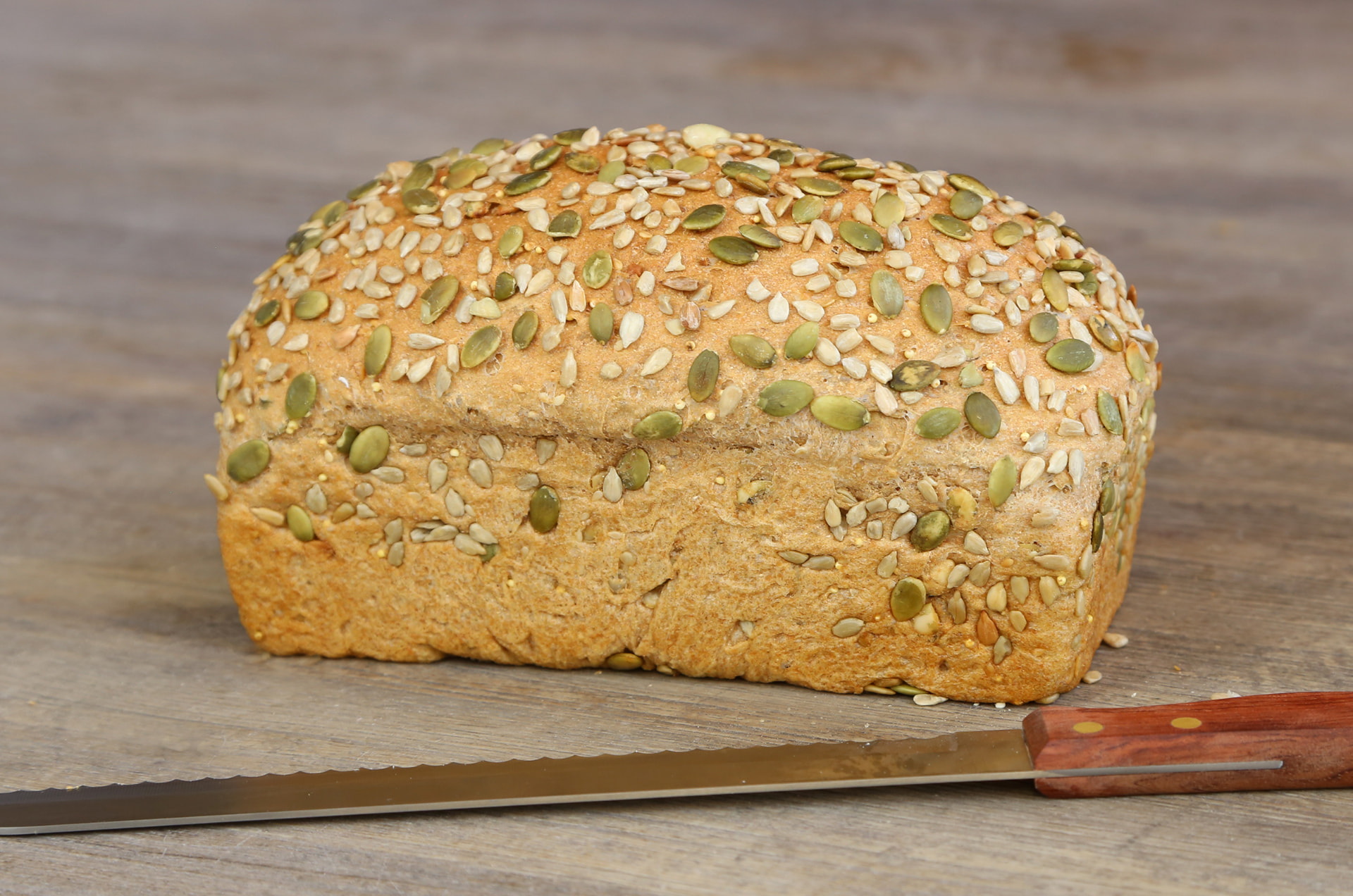 Dakota loaf covered in seeds and grains on a wooden board