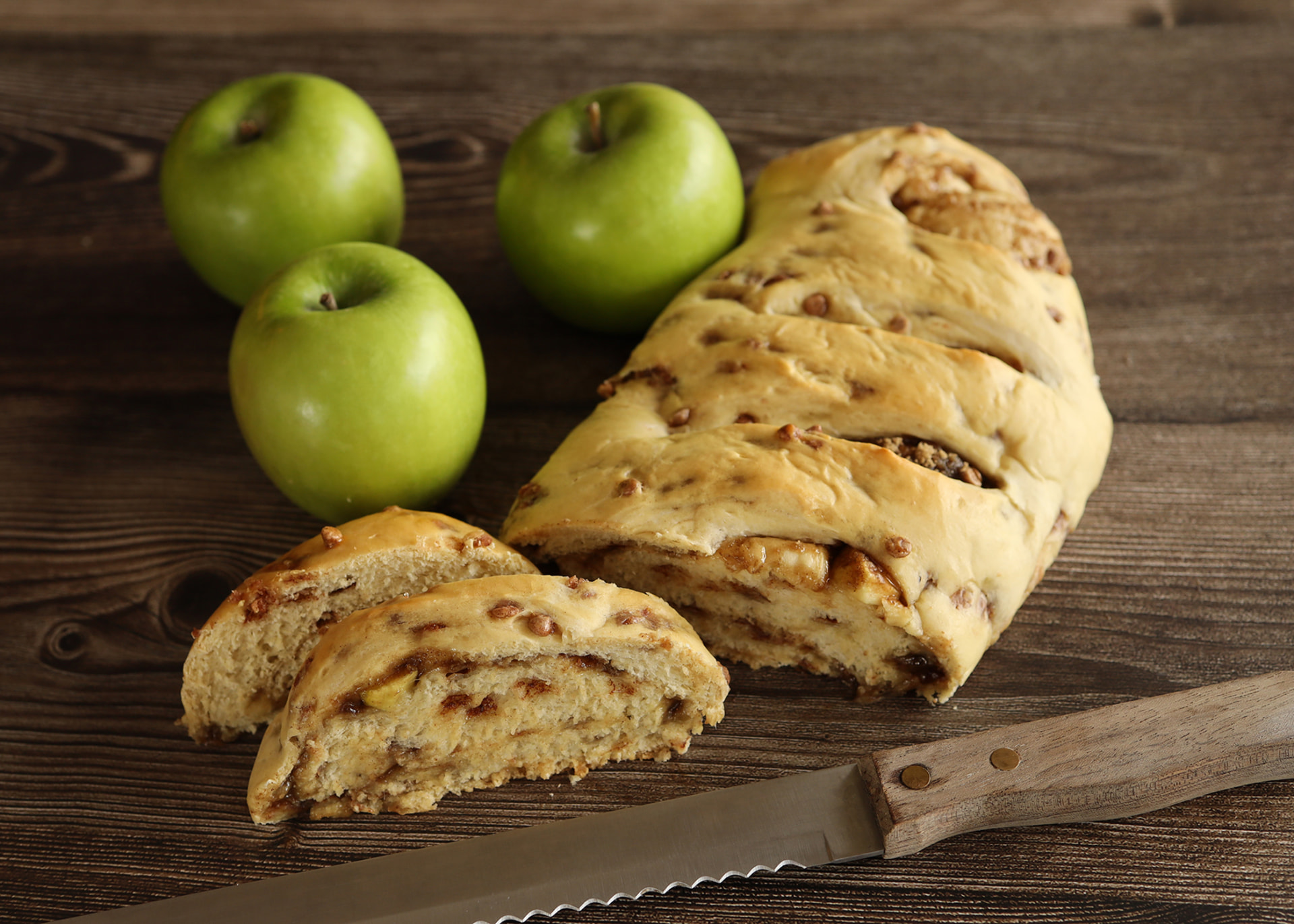 Apple Pie Swirl loaf sliced to reveal apple-cinnamon filling next to green apples